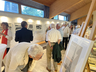 Ein Mann betrachtet bei der Vernissage eine Zeichnung genauer und beugt sich vor.
