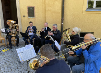 Blechbläser sitzen im Halbkreis im Innehof von Schloss Neuburg und spielen ein Lied.