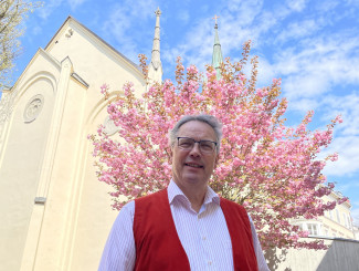 Dekan Jochen Wilde vor einem blühenden Baum im Kirchgarten von St. Matthäus
