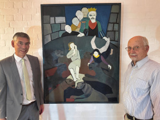 Pfarrer Muschler und Michael Nerud stehen vor dem Gemälde "Daniel in der Löwengrube".