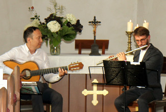 Die zwei Musiker von Duo Nova sitzen mit Gitarre und Querflöte vor dem Altar der Martin-Luther-Kirche.