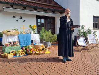 Ansprache von Pfarrer Weinmaier vor dem improvisierten Altar mit den Erntegaben.
