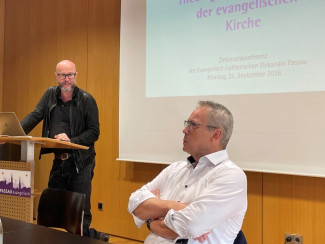 Redner Ralf Frisch am Pult und Dekan Wilde sitzend