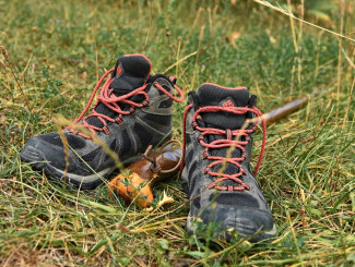 Wanderschuhe und ein Wanderstab liegen in der Wiese