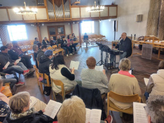 Michael Martin am Piano umringt von Sänger:innen