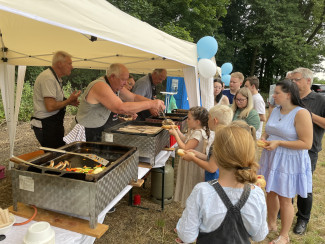 Einige Menschen stehen in eine Schlange am Grillwürstchenstand an.
