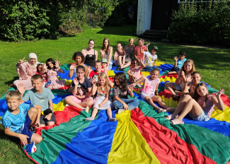 KInder sitzten auf einen Sprungtuch im Garten der evangelischen Kirche Pocking.