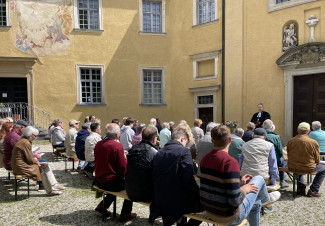 Die Gottesdienstbesucher sitzen im Innenhof von Schloss Neuburg auf Bierbänken.