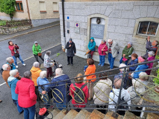 Die Ausflugsgruppe steht vor dem Haus in dem Bonhoeffer untergebracht war. Es regnet.