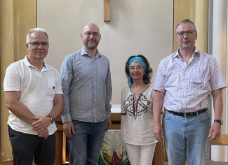 Dr. Carsten Lenk,  Stefan Penninger, Patricia Vásquez Covarrubias und Dekan Jochen Wilde stehen vor dem Altarraum der evangelischen Stadtpfarrkirche in Passau.