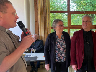 Pfarrer v. Kölichen mit Mikrofon und Karin und Jürgen Wisgalla