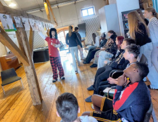 Die Jugendlichen betrachten am Gebälk aufgehängte Bilder.