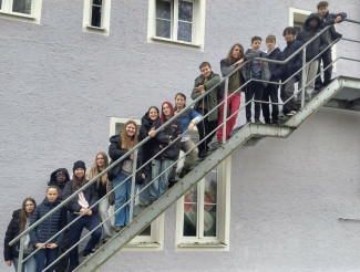 Die Konfis stehen aufgereiht zum Abschlussfoto auf einer Außentreppe eines Gebäudes.