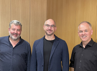 Ralf Albert Franz, Johannes Keller und Andreas Unterguggenberger stehen in einer Reihe vor einem Flügel im Evangelischen Zentrum.