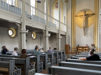Teilnehmer:innen des Dekanatskonvent Kirchenmusik sitzen verstreut in den Bänken in der Stadtpfarrkirche und lauschen der Orgelmusik.