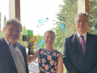 Im lichtdurchfluteten Erker des Katharina-von-Bors-Hauses in Eging am See stehen Andreas Köckhuber, Annalena Hardinge mit Glaskreuz in der Hand und Dekan Jochen Wilde..