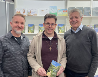 Die dfei Autoren stehend vor dem Messestand von Crismon auf der Leipziger Buchmesse.