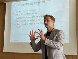 Toni Schuberl bei der Lesung im Evangelischen Zentrum. Im Hintergrund die Präsentation.