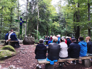 Menschen sitzen auf Bänken in der Naturkapelle