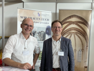 Die Pfarrer Arne Schnütgen und Stephan Schmoll vor dem Stand des Dekanats auf der Hochzeitsmesse.