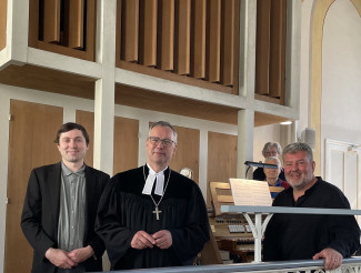 Orgelbauer Fruth, Dekan Wilde und Kantor Franz stehen auf der Empore vor der Orgel.