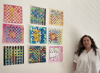 Manuela Schubert steht neben den an eine Wand gepinnten bunten Kunstwerken.