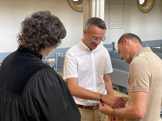 Hochzeitspaar bindet sich gegenseitig ein Segensbändchen ans Handgelenk