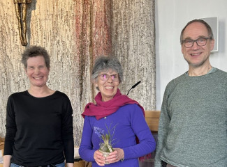 Vorstellung der neuen Sekretärin. ##sie steht zwischen den beiden Pfarrer:innen und freut sich.