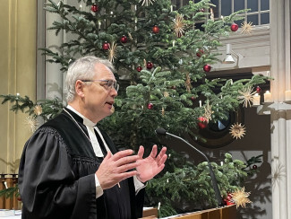 Dekan Jochen Wilde steht am Pult der Stadtpfarrkirche und predigt. Im Hintergrund steht der Weihnachtsbaum.