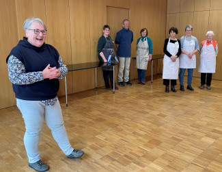 Sabine Aschenbrenner (li) stellt den Gästen das Kochteam vor: (v.l.n.r.) Helga Rech, Helmut Ritter, Inge Spannbauer, Hannelore Franke, Elisabeth Smola und Margarete Hirblinger.