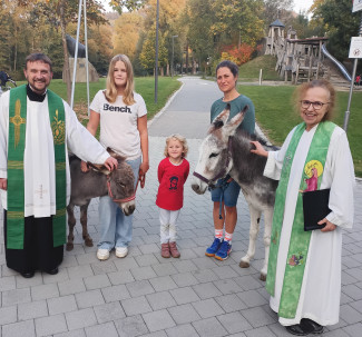 Zwei Esel und ihre Besitzer. Links und rechts davon der Pfarrer Dengler und die evangelische Diakonin Neumann-Beiler