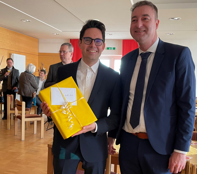 Mit offenen Armen wurde Pfarrer Steensen (li) von seinem katholischen Kollegen Alexander Aulinger empfangen. Sein Willkommensgeschenk hält er in Händen.